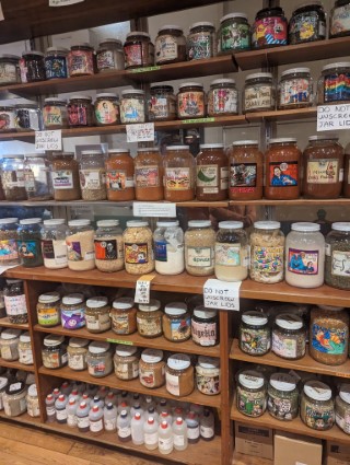 Photo taken at Pike Place Market of a wall with shelves installed on every height, packed to the brim with different looking jars and labels.