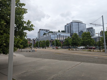 Photo taken from a walking path next to a tram line of some tall glass buildings.