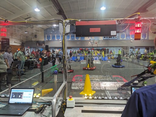 Photo of the arena, where our robot is seen trying to pick up a cube, among other robots who are also wheeling around and doing stuff.