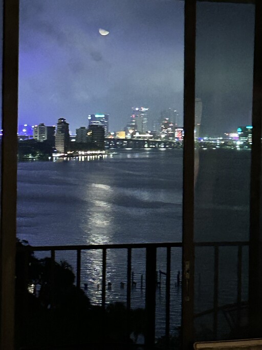 View through open glass sliding door of moon over St Johns River and City of Jacksonville, Florida